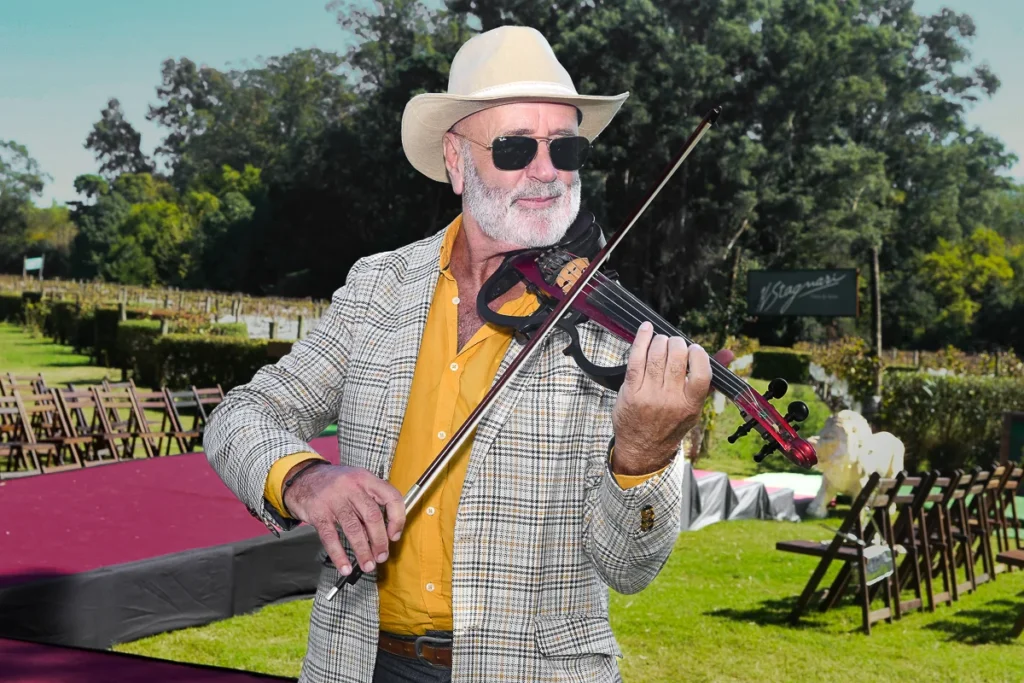 Edison Mouriño tocando el violín eléctrico en un evento empresarial al aire libre en una bodega en Uruguay